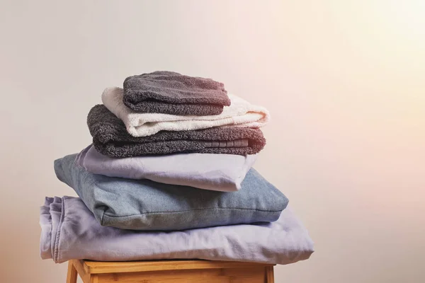 Une pile de textiles en lin sur une petite chaise en bois — Photo