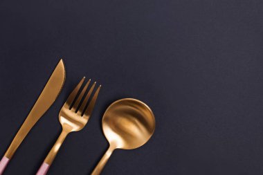 Siyah arkaplanda zarif altın çatal bıçak takımı