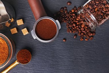 Kahve filtresi ve kavrulmuş fasulyeler siyah arka planda etrafa saçılmış.