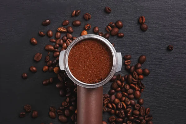 Coffee filter holder with and roasted beans scattered around on black background, — Stock Photo, Image