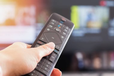 Televizyonun önünde uzaktan kumandayı elinde tutan kadınların yakın çekimi.,