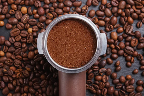 Coffee filter holder and roasted beans scattered on black background — Stock Photo, Image