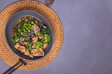 Gri taş masada teriyaki tavuklu ve brokolili soba şehriyesi.