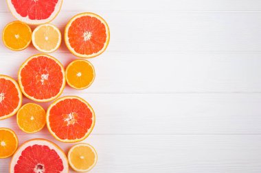 Düz kompozisyon, beyaz ahşap zemin üzerinde farklı narenciye meyveleri yarımları ile yatıyordu