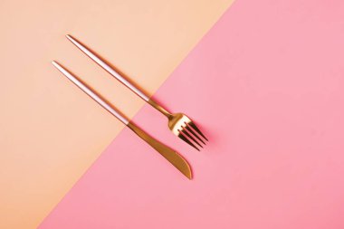 Renkli blok arka planında şık pembe ve altın çatal bıçak seti
