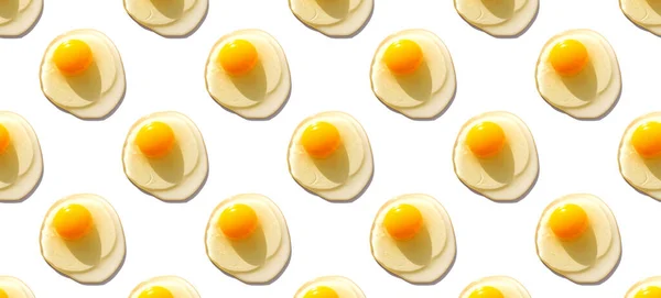 Creatief minimalistisch patroon met rauwe eieren met dooiers op witte achtergrond. — Stockfoto