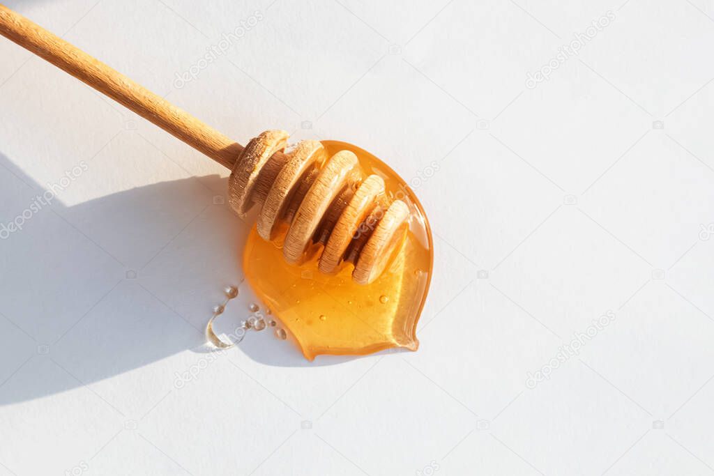 Wooden honey dipper in honey on white background