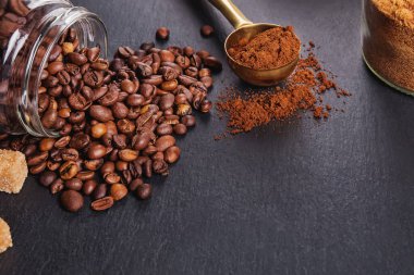 Kavrulmuş kahve çekirdekleri ve siyah masada öğütülmüş kahve.