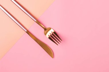 Renkli blok arka planında şık pembe ve altın çatal bıçak seti