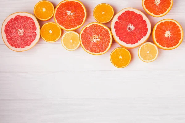 Flat lay composition with halves of different citrus fruits on white wooden background, top view — Stock Photo, Image