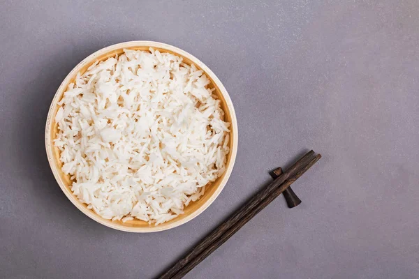 Cuenco de arroz de jazmín cocido y palillos en la mesa gris — Foto de Stock