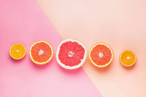Кусочки различных цитрусовых на розовом фоне — стоковое фото