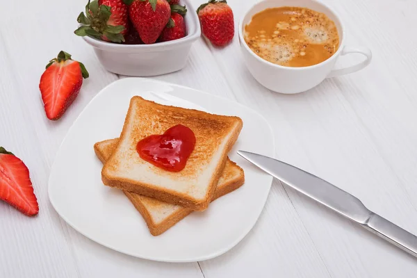 Färska rostat bröd med jordgubbssylt i hjärtform, kaffe och jordgubbar — Stockfoto