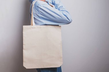 Mavi gömlekli kız boş pamuklu çanta taşıyor.,