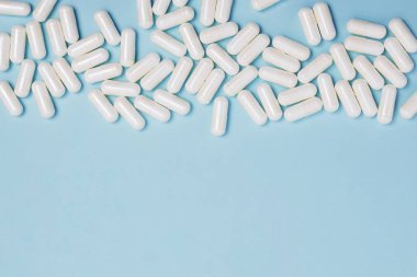 Mavi arka planda, kopyalama alanı olan beyaz tıbbi haplar