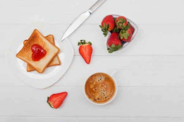 Desayuno con pan tostado y mermelada en forma de corazón, fresas y café — Foto de Stock