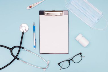 Dosyada boş bir kağıt ve steteskop ile tıbbi maket, tıbbi maske ve diğer doktor aletleri.,