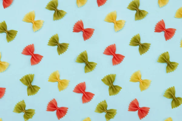 Kolorowy włoski makaron farfalle lub łuki na niebieskim tle, — Zdjęcie stockowe