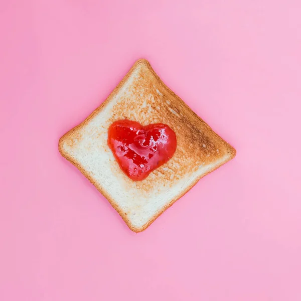 Toastbrot mit Erdbeermarmelade in Herzform auf rosa Hintergrund — Stockfoto