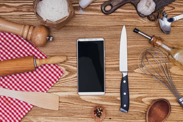 Різні посуд і смартфон з порожнім екраном на дерев'яному фоні — стокове фото