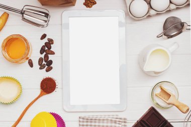 Beyaz masadaki metin veya resim için boş ekranı ve yeri olan pişirme ve tablet malzemeleri ve araçları
