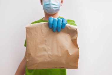 Yeşil tişörtlü, koruyucu eldivenli ve maskeli bir teslimatçı.