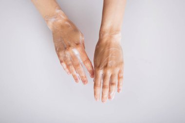 Beyaz arka planda sabunlu köpüklü kadın elleri