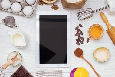 Beyaz masadaki metin veya resim için boş ekranı ve yeri olan pişirme ve tablet malzemeleri ve araçları