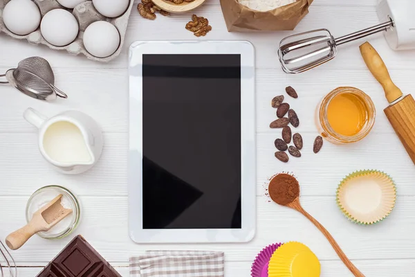 Zutaten und Werkzeuge zum Backen und Tabletten mit leerem Bildschirm und Platz für Text oder Bild auf weißem Tisch — Stockfoto