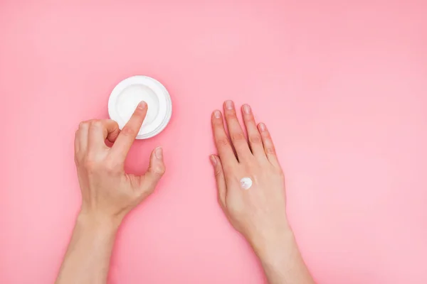 Mujer hidratando su mano con crema cosmética con espacio de copia sobre fondo rosa en estilo minimalista . — Foto de Stock