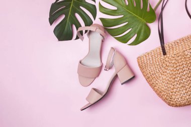 Canavar yeşili yapraklar, kadın sandaletleri ve saman torbası. Düz yatış, üst görünüm.