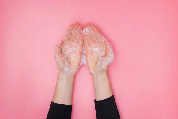 Mãos femininas com espuma borbulhante sabão no fundo rosa — Fotografia de Stock