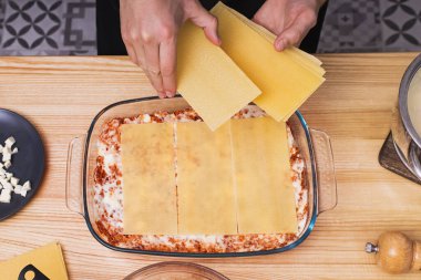 Mans eller cam tepside lazanya katmanları yapıyor, üst manzara.