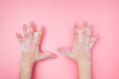 Pembe arka planda sabunlu köpüklü kadın elleri,