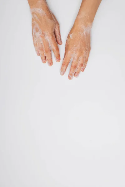 Γυναικεία χέρια με σαπουνόφουσκες αφρώδες σε λευκό φόντο. — Φωτογραφία Αρχείου