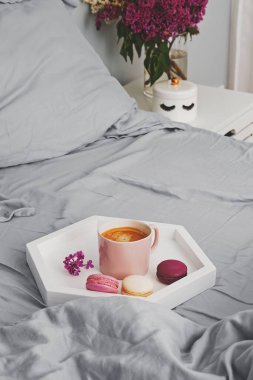 Yatağın üzerinde duran taze kahve ve badem kurabiyeli tepsi.