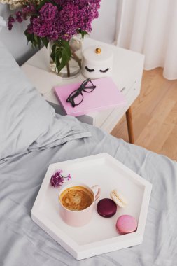 Yatağın üzerinde duran taze kahve ve badem kurabiyeli tepsi.