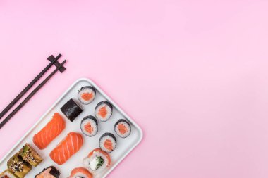 Taze suşi, rulo ekmek ve çubuklar pembe masada.,