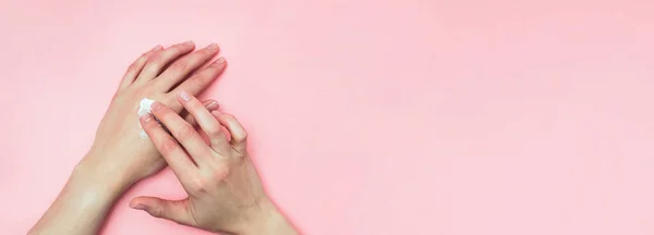 Mulher hidratando a mão com creme cosmético com espaço de cópia em fundo rosa no estilo minimalismo . — Fotografia de Stock