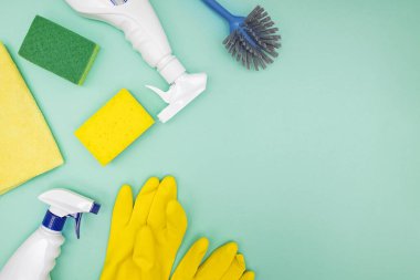 Yeşil arkaplanda temizlik araçları ve malzemeler, üst görünüm.