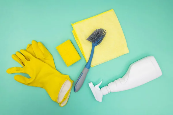 Cleaning tools and supplies on green background, top view.