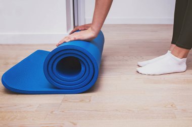 Yoga dersinden sonra paspası yuvarlanan ya da evde egzersiz yapan bir kadın..