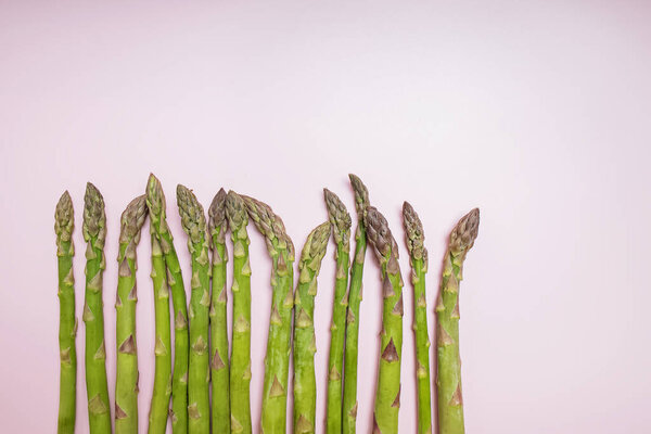 Fresh green asparagus on a pink background with copy space