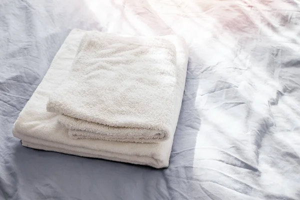 Toalhas limpas brancas na cama com roupa de cama cinza . — Fotografia de Stock