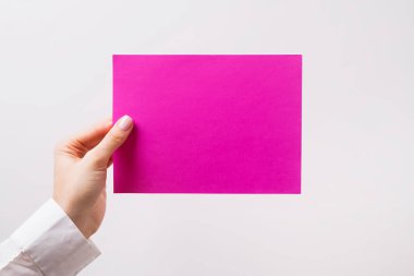 Kadın eli boş pembe bir kağıt tutuyor.