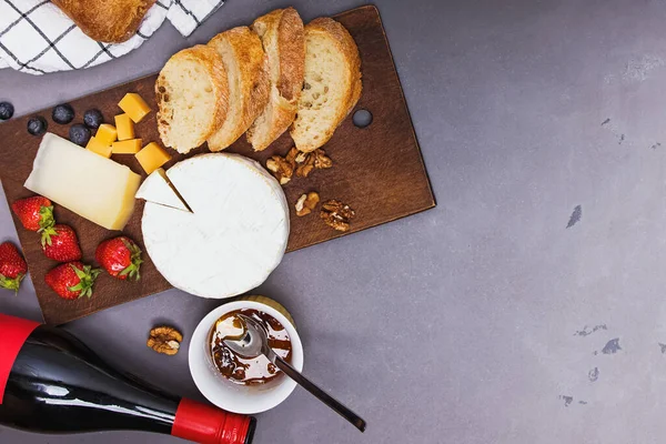 Queijo, pão de vinho e morangos na mesa de pedra cinzenta . — Fotografia de Stock