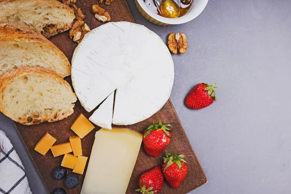 奶酪、葡萄酒面包和草莓放在灰色石桌上. — 图库照片