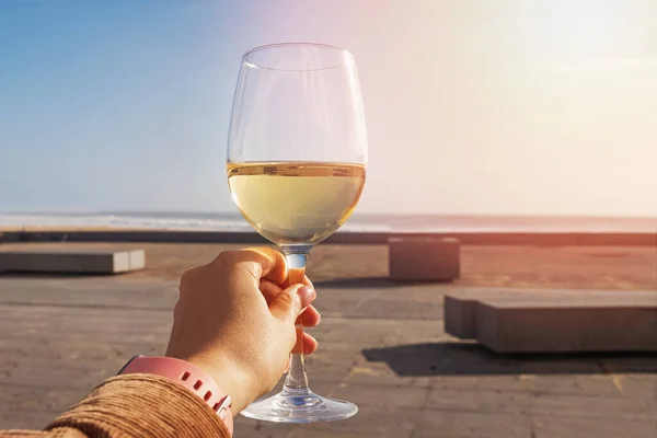 Mão das mulheres segurando um copo de vinho branco no terraço aberto de um restaurante de rua — Fotografia de Stock