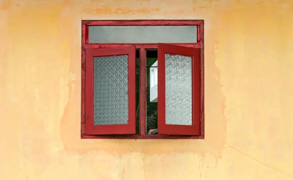 Janela vermelha com persianas na fachada da casa amarela — Fotografia de Stock