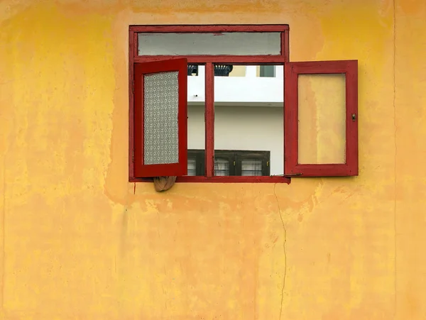 Janela grunge velha vermelha na fachada da casa amarela — Fotografia de Stock